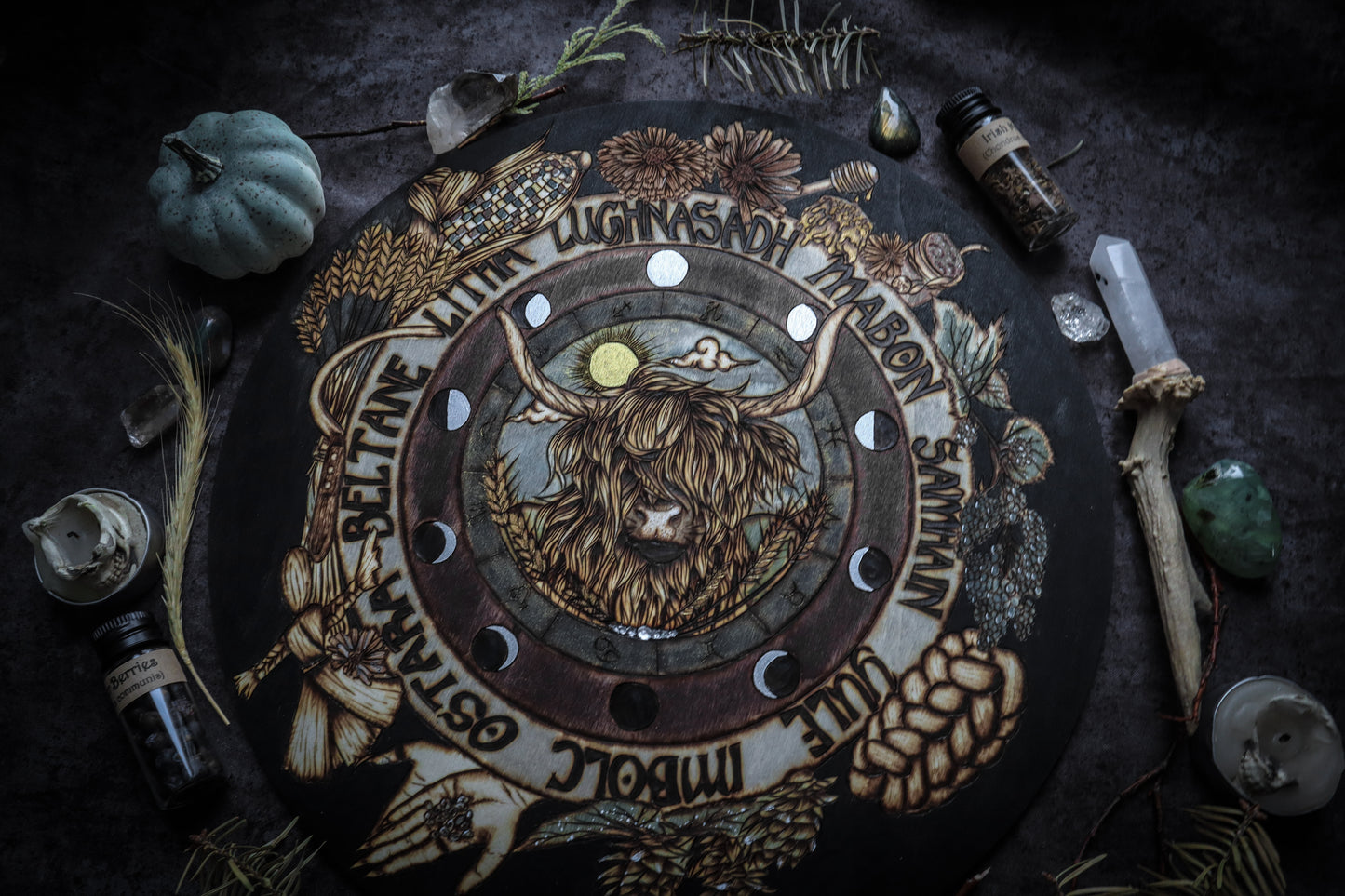 This witchy woodburned wheel of the year is handcrafted to include imagery that invokes the themes of Lughnasadh such as a Highland cow, rainbow corn, scythe, wheat, bread, runes, corn dolly, hops, honey, etc while also including moon phases, astrological symbols, and the sabbath's of the pagan year. Handpained, this wheel of the year also includes sparkly metallic accents which grab the light from across the room. Add this wheel of the year to your space or altar to celebrate the celtic pagan season.