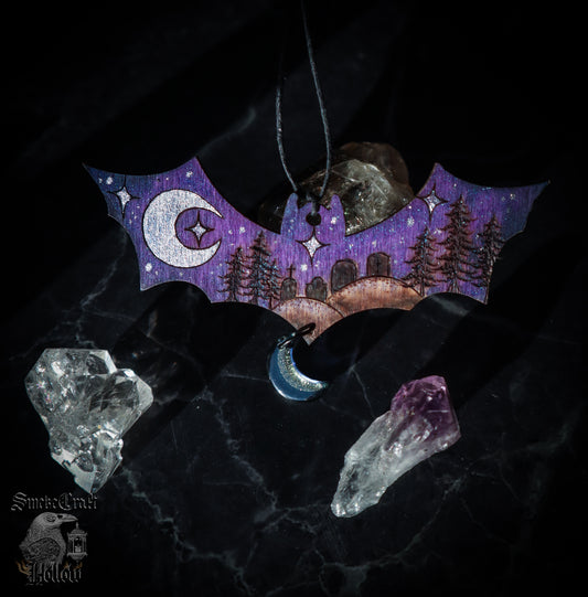 Halloween bat ornament with blue and purple colouring, silver moon, and haunted cemetery. 