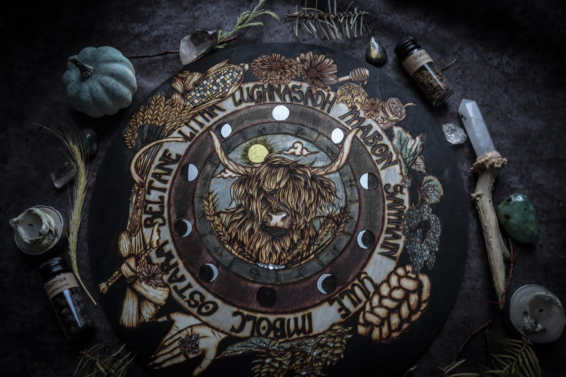 This witchy woodburned wheel of the year is handcrafted to include imagery that invokes the themes of Lughnasadh such as a Highland cow, rainbow corn, scythe, wheat, bread, runes, corn dolly, hops, honey, etc while also including moon phases, astrological symbols, and the sabbath's of the pagan year. Handpained, this wheel of the year also includes sparkly metallic accents which grab the light from across the room. Add this wheel of the year to your space or altar to celebrate the celtic pagan season.