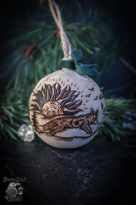 Handmade christmas ornament woodburned on bauble with woodland scene of fox chasing a hare on winter solstice for pagan yule Christmas at www.smokecrafthollow.com